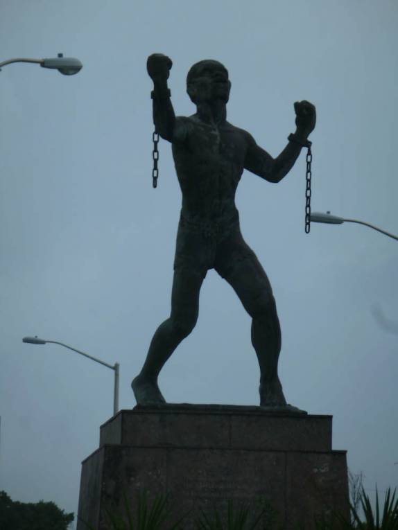 Bela escultura comemorando o fim da escravidão, na estrada próxima à Bridgetown, capital de Barbados Bela escultura comemorando o fim da escravidão, na estrada próxima à Bridgetown, capital de Barbados
