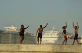 Adolescentes brincando no pier com cruzeiros ao fundo