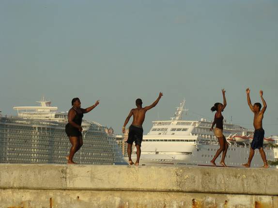 Adolescentes brincando no pier com cruzeiros ao fundo Adolescentes brincando no pier com cruzeiros ao fundo