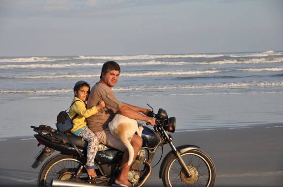 Moto com um motorista e dois passageiros, na Juréia-SP Moto com um motorista e dois passageiros, na Juréia-SP