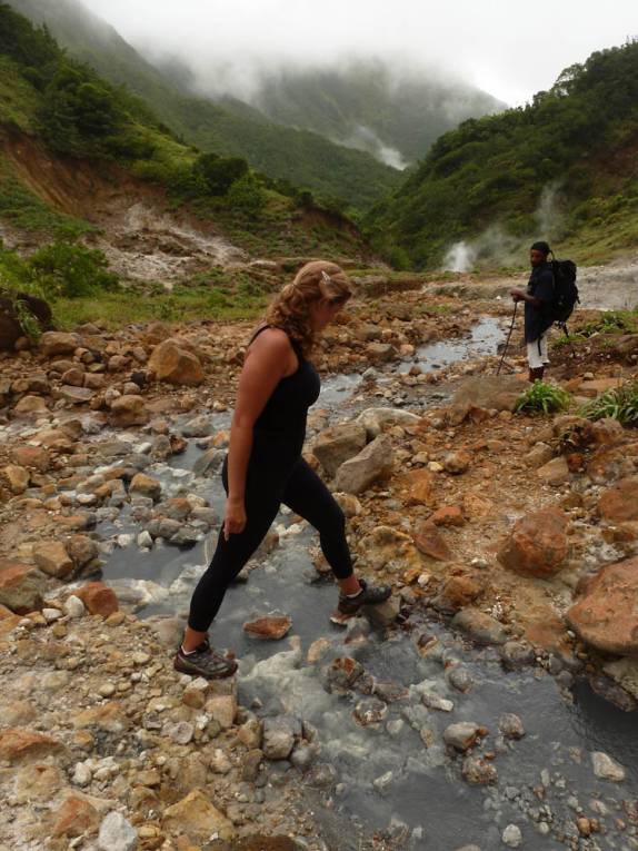 Saltando pequeno riacho de águas ferventes no Vale da Desolação, na trilha do Boiling Lake, no Trois Pitons National Park, em Dominica, no Caribe Saltando pequeno riacho de águas ferventes no Vale da Desolação, na trilha do Boiling Lake, no Trois Pitons National Park, em Dominica, no Caribe