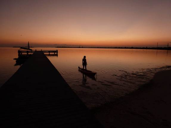 Voltando à terra firme depois de remar pelo entardecer na baía em frente ao nosso hotel em Little Cayman, nas Ilhas Caiman Voltando à terra firme depois de remar pelo entardecer na baía em frente ao nosso hotel em Little Cayman, nas Ilhas Caiman